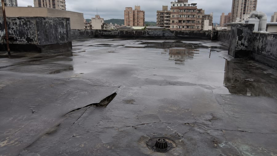 平屋頂防水層老化、局部起泡與積水情況，呈現屋頂現場常見異常。